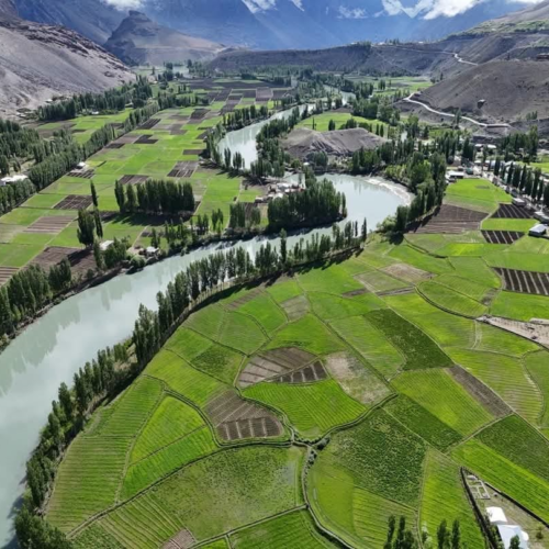 Deep blue Phander Lake surrounded by green fields and mountains in Ghizer Valley, Pakistan