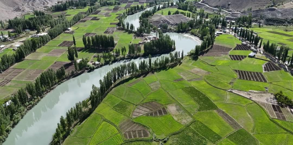 Deep blue Phander Lake surrounded by green fields and mountains in Ghizer Valley, Pakistan