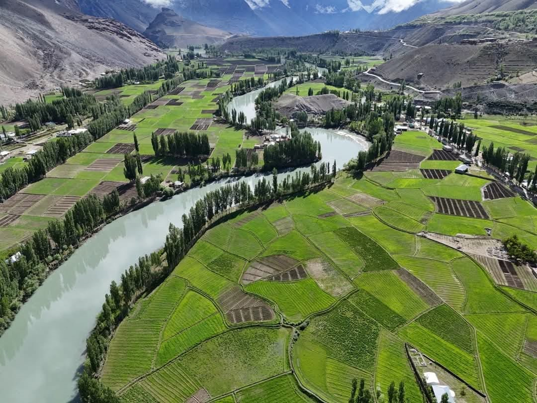 Deep blue Phander Lake surrounded by green fields and mountains in Ghizer Valley, Pakistan