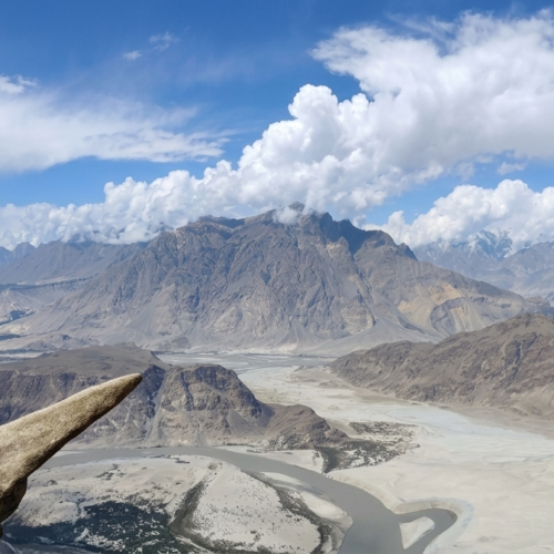 Hiker standing on the narrow granite ledge of Marsur Rock overlooking the Indus River, Skardu