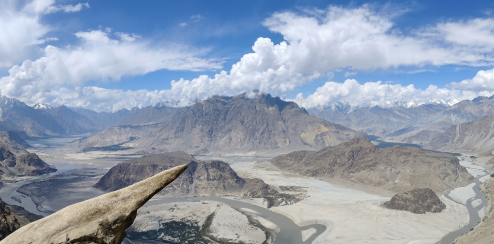 Hiker standing on the narrow granite ledge of Marsur Rock overlooking the Indus River, Skardu