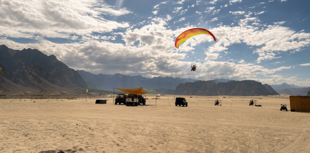 Paraglider soaring over the golden sand dunes of Sarfaranga Cold Desert near Skardu